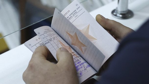 Военный билет в руках мужчины в военном комиссариате (Фото Кирилла Кухмаря / ТАСС)