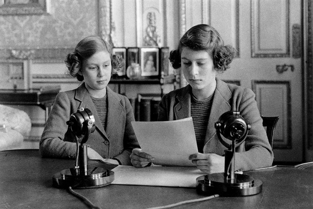 1940 год. Елизавета впервые обращается к нации по радио в связи с началом немецких воздушных атак на Британию (слева - принцесса Маргарет)